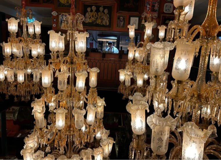 A chef at work surrounded by very large Indian chandeliers.