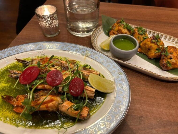 Two plates of food, one of grilled prawns and one of grilled chicken 