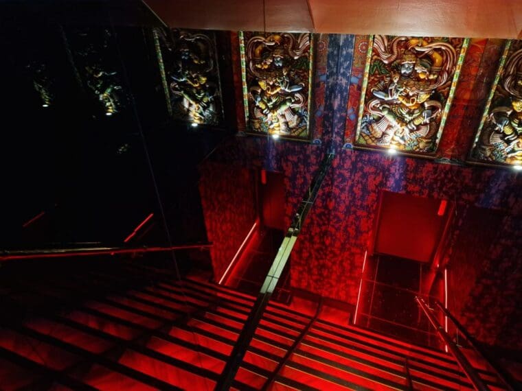 Steep staircase with red lights and mirrors down to Holy Brew speakeasy cocktail bar at Dalchini restaurant