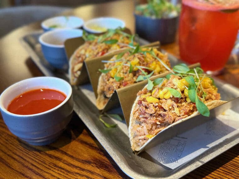 Chicken tacos in a zigzag metal rack and dish of red chilli sauce served at Waterfront Street Kitchen and Bar at Royal Victoria Dock.