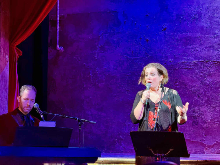 Christine Bovill on stage performing Piaf Revisited at Wilton's Music Hall, East London. Pianist, Michael Roulston is to the left.
