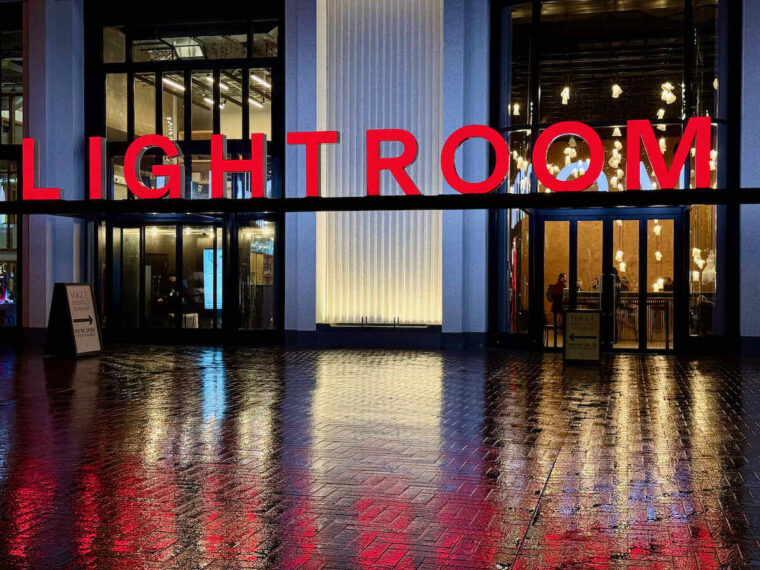 Exterior night view of Lightroom venue, with signage in bold red lights. The ground is wet from rain reflecting the red lights on the floor.