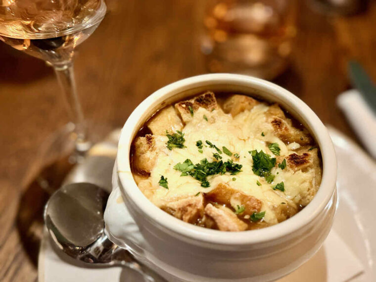 French onion soup topped thickly with Gruyère and croutons, in a white traditional lion's head soup bowl. As served at The Royal Forest, Epping Forest, Heartwood Inns. 