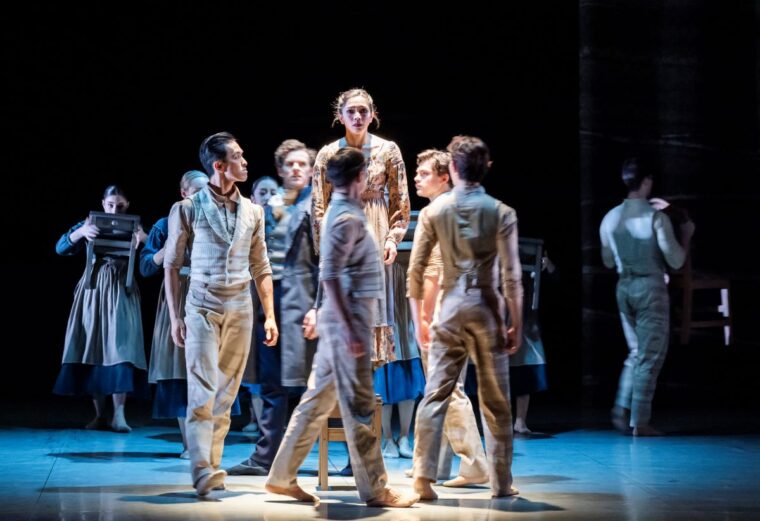 Rachael Gillespie as Young Jane surrounded by D-Men. She stands on a chair, having been punished by her schoolmaster. Other schoolgirls dance behind her. Credit, Tristram Kenton