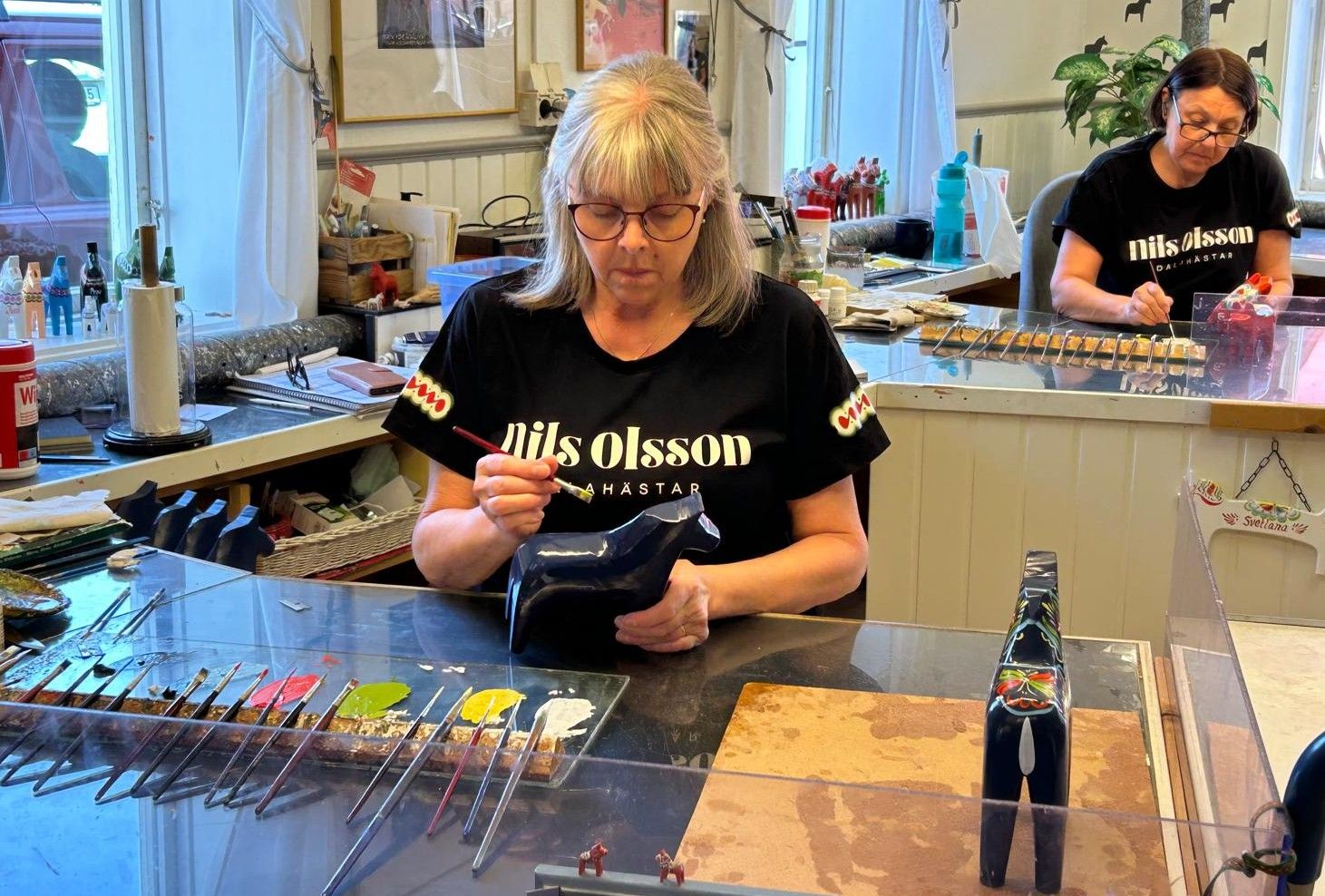Artists hand painting the distinctive patterns onto the Dala horses in Sweden.