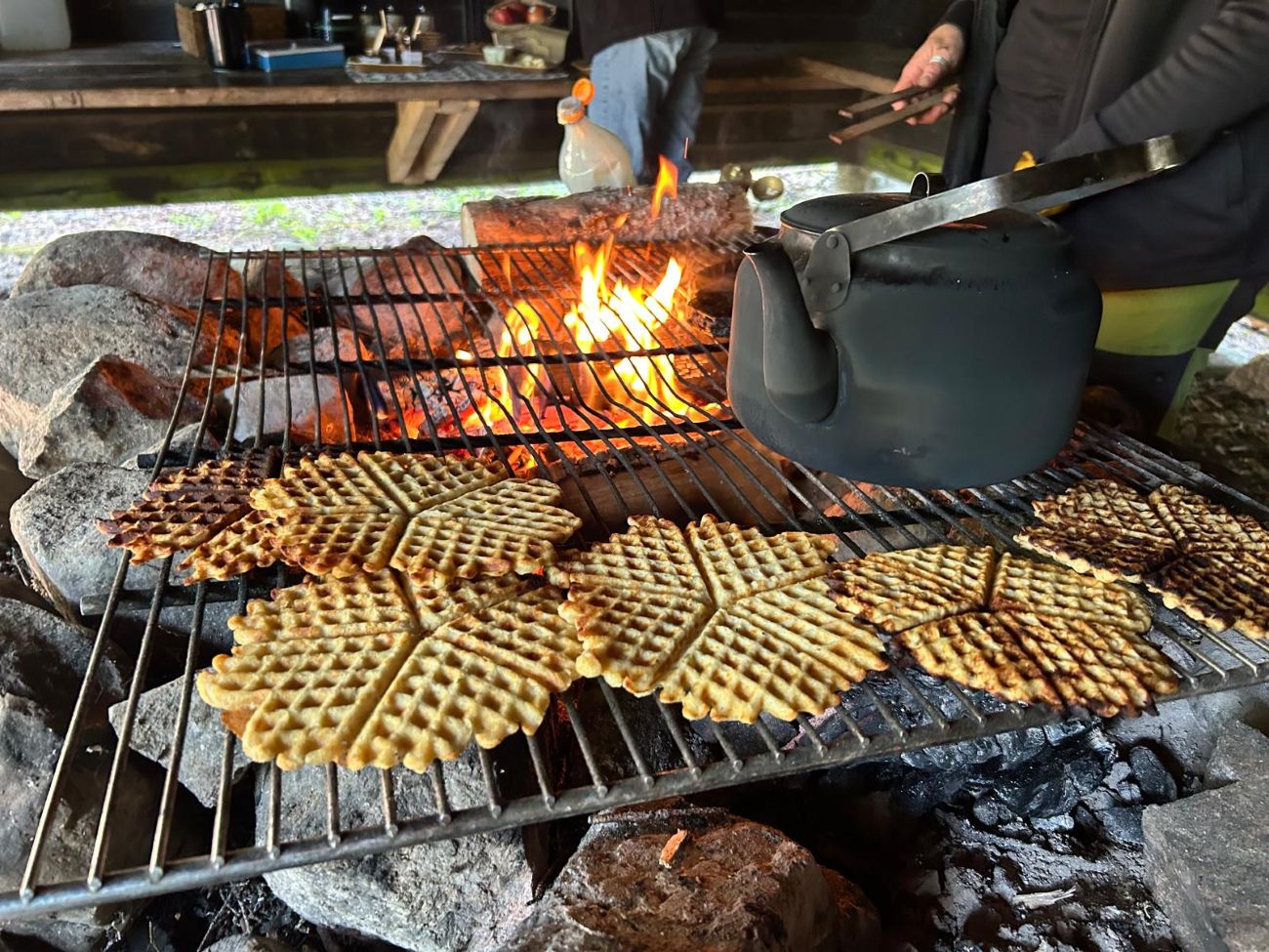 Picture of waffles being cooked on an open camp fire during a hike in a forest in Sweden.