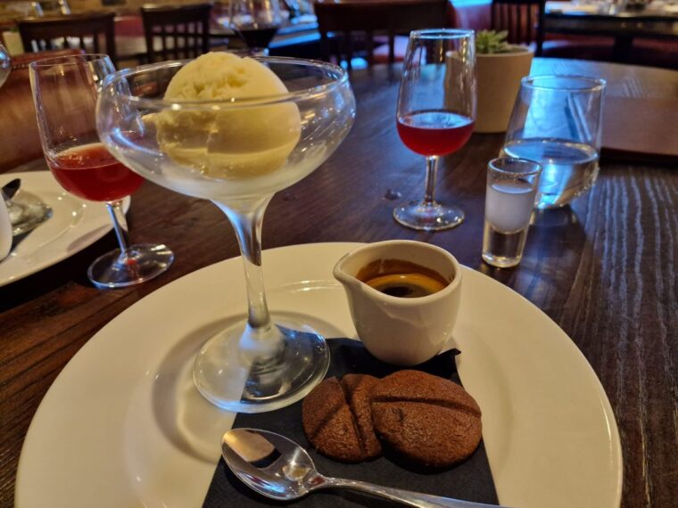 A coup glass containing a scoop of vanilla ice cream alongside a small mug of coffee as ingredients to construct the Italian dessert, affogato.