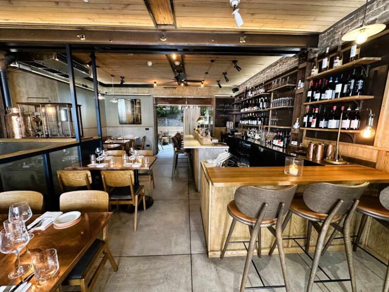 Fire and Wine is decorated in a rustic chic style with brass table tops and tree trunk legs, brass objects, wooden ceilings and overhead fans