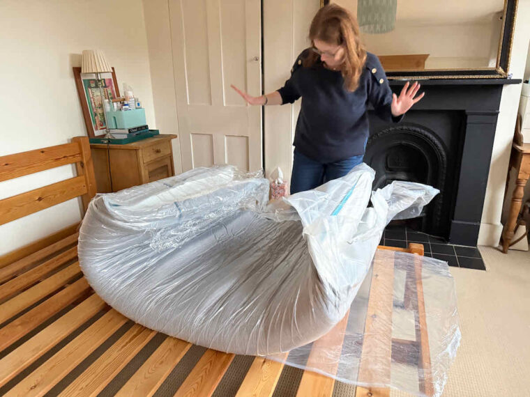 Unrolling the Simba mattress: a woman stands back watching the mattress expand from its packaging.