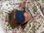 Sleeping woman with blue satin eye mask and floral duvet cover