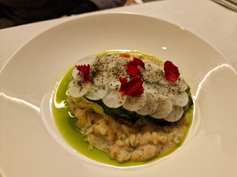 A main course dish of cod fillet wrapped in hispi cabbage with kohlrabi scales and a cassoulet at Orion by Alex Webb
