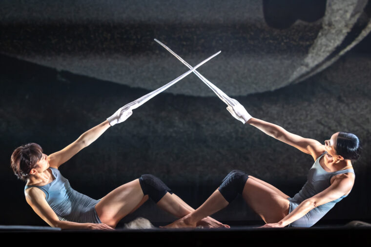 Two female dancers brandish white sticks in Neon Dance's Last and First Men