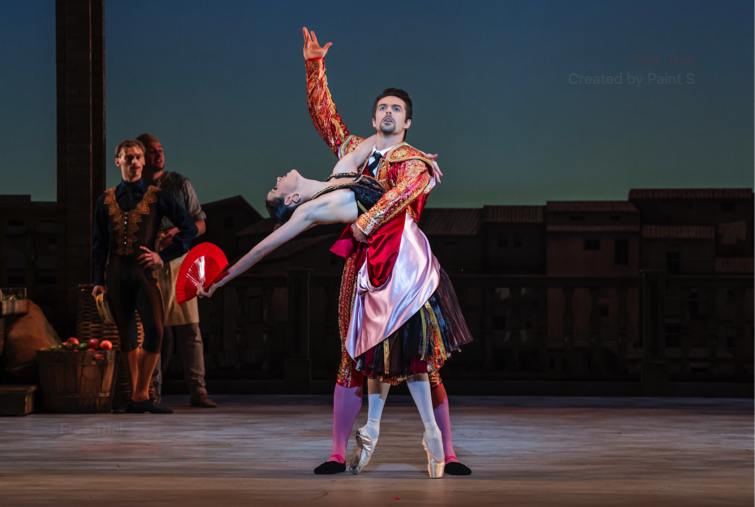 The matador Espada faces forward with an arm raised while the other arm supports Mercedes standing on pointe, back bent at the end of their pas de deux.
