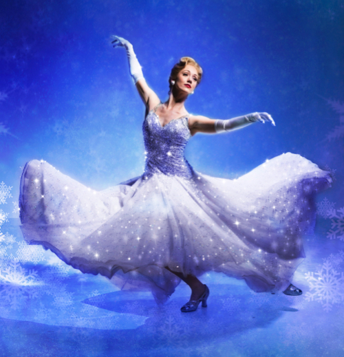Cinderella, in an ample white, glittery ball down and white gloves is surrounded by clouds against a blue sky