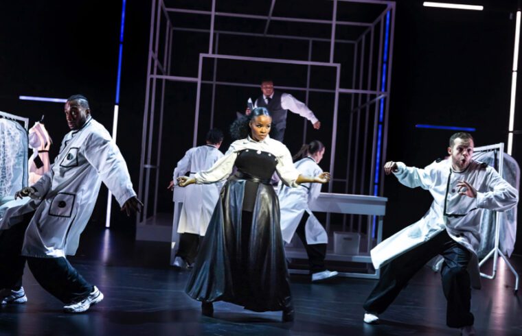 A group of hip hop dancers surround s central female figure in a shiny black dress, who is clearly the boos