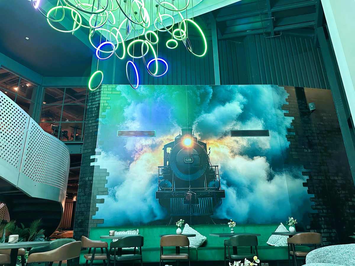 The entrance lobby at Aloft By Marriott Manchester has a large mural of a steam train and an eye-catching light installation