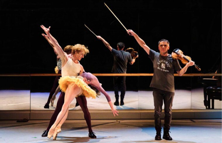 The McRae/Vassilev Project: the final pose. dressed in practice clothes, McRae has the right arm raised, and with the left supports Lamb in a deep backbend. Vassilev raises the arm holding the bow.