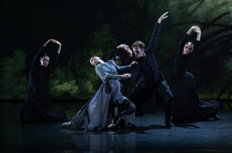 Firebird - A Double Bill A man dressed in all black dominates a woman in a long grey dress. She appears to be resisting him. Three black-clad women stand at the back